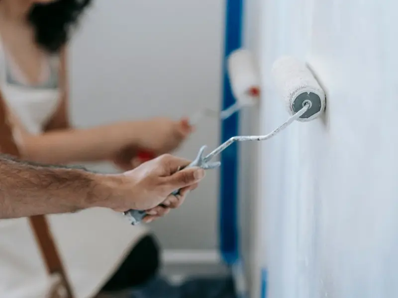 Wohnungsübergabe in Erding: Hände frischen eine Wand mit der Farbrolle auf